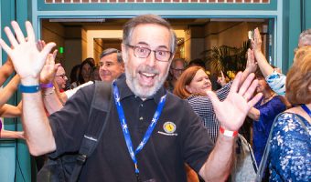 A guy with his hands up laughing at a conference