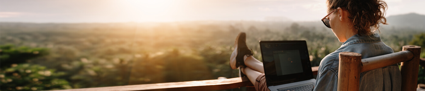 Woman sitting on a porch with her feet up on a laptop