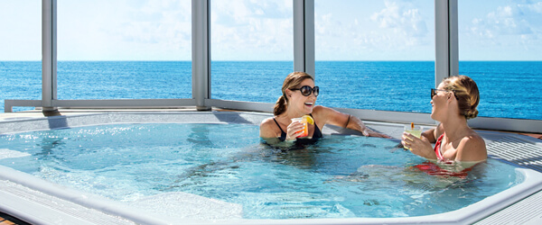 Two women drinking in a hot tub at sea.