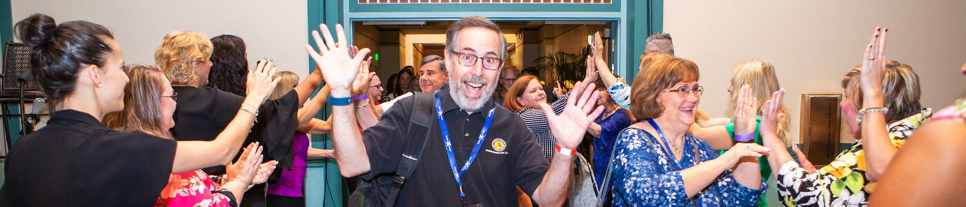 A guy with his hands up laughing at a conference